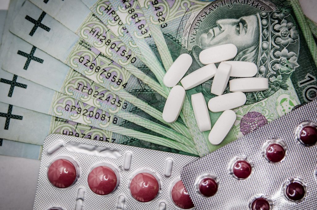 tabletki i blistry leków na tle banknotów stuzłotowych