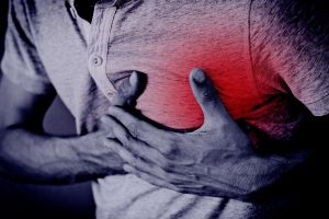 Zdjęcie monochromatyczne z podreślonym czerwonym kolorem obrazem mężczyzny chwytającego się za pierś w związku z odczuwanym nagłym bólem w okolicy serca (atakiem serca)