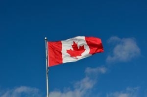 Flaga Kanady łopocząca na tle niebieskiego nieba
