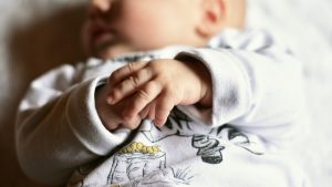 Rączki niemowlęcia leżącego spokojnie na łóżeczku