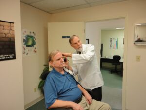pacjent na wózku w pokoju szpitalnym ma badany słuch przez lekarza