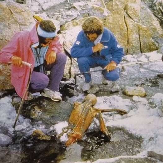 Dwóch mężczyzn przykucających w pobliżu szczątków człowieka, odkrytych w lodowców w górach
